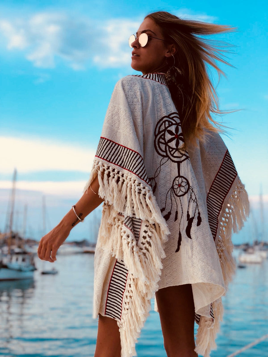 Woman wearing linen cape in front of a port